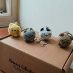 Four small crochet cat toys on a cardboard box with 'Manna Giftistry' branding.