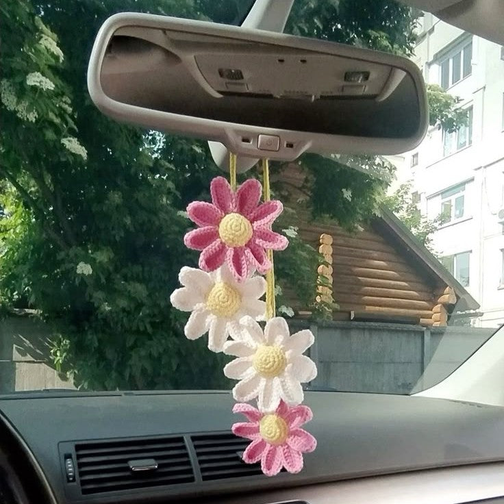 Car interior with a floral crochet ornament hanging from the rearview mirror.